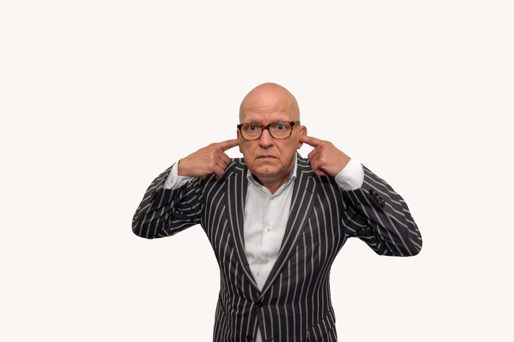 man wearing corporate attire and covering ears